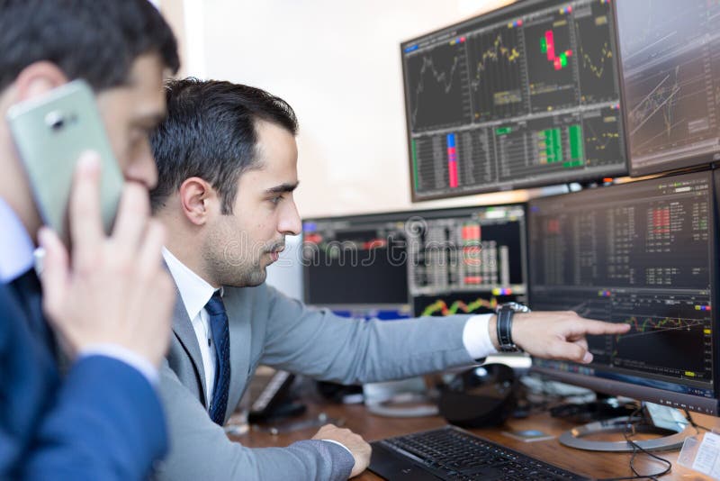 Businessmen trading stocks online. Stock brokers looking at graphs, indexes and numbers on multiple computer screens. Colleagues in discussion in traders office. Business success concept. Businessmen trading stocks online. Stock brokers looking at graphs, indexes and numbers on multiple computer screens. Colleagues in discussion in traders office. Business success concept.