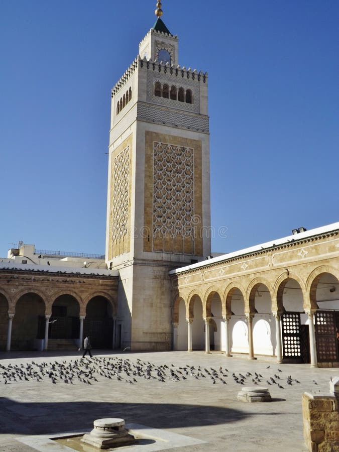 The courtyard of the Al-Zaytuna mosque and Minaret in Tunis, Tunisia. Many pigeons are in the patio. North Africa. The courtyard of the Al-Zaytuna mosque and Minaret in Tunis, Tunisia. Many pigeons are in the patio. North Africa.