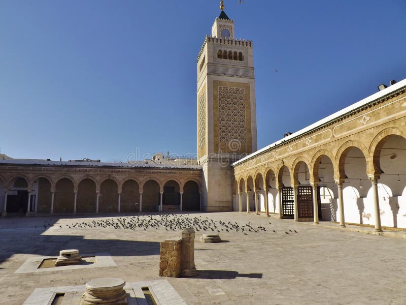 The courtyard of the Al-Zaytuna mosque and Minaret in the Medina of Tunis, Tunisa, Africa. Many pigeons are in the patio. The courtyard of the Al-Zaytuna mosque and Minaret in the Medina of Tunis, Tunisa, Africa. Many pigeons are in the patio.