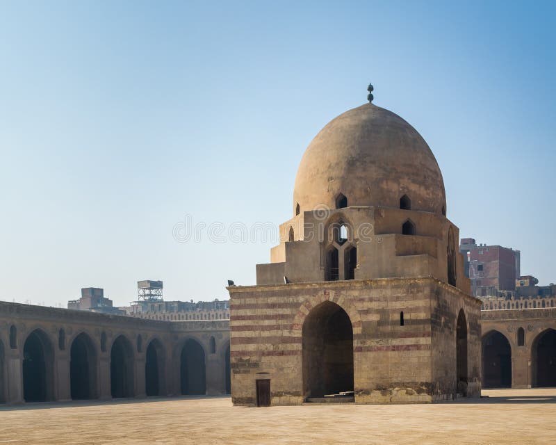 Courtyard of Ibn Tulun public historical mosque with ablution fountain and arched passages surrounding the courtyard in the background, Sayyida Zaynab district, Medieval Cairo, Egypt. Courtyard of Ibn Tulun public historical mosque with ablution fountain and arched passages surrounding the courtyard in the background, Sayyida Zaynab district, Medieval Cairo, Egypt