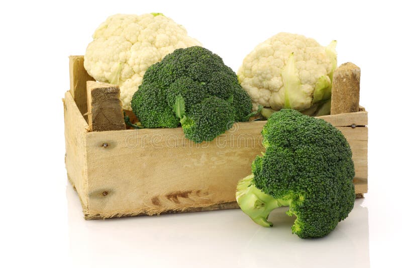 Fresh cauliflower and broccoli in a wooden crate on a white background. Fresh cauliflower and broccoli in a wooden crate on a white background