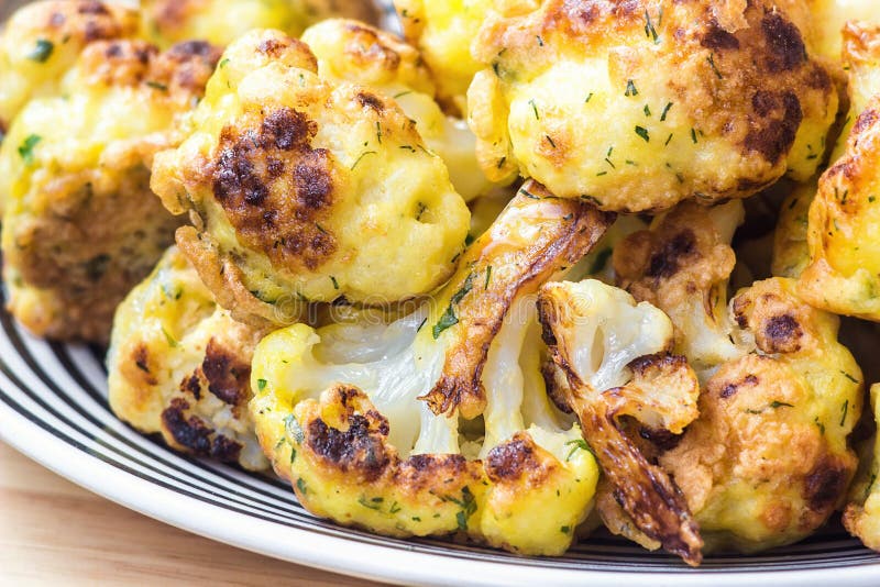 Roasted cauliflower in white plate on wooden background close up. Roasted cauliflower in white plate on wooden background close up.