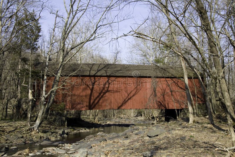 A red covered bridge spanning a stream in the woods of Bucks County, Pennsylvania. A red covered bridge spanning a stream in the woods of Bucks County, Pennsylvania.