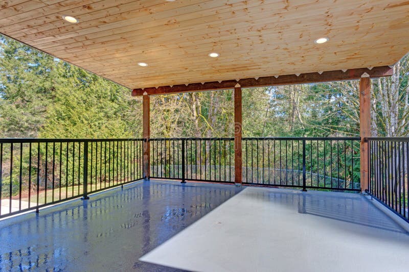 Covered deck with wooden ceiling and iron handrails.