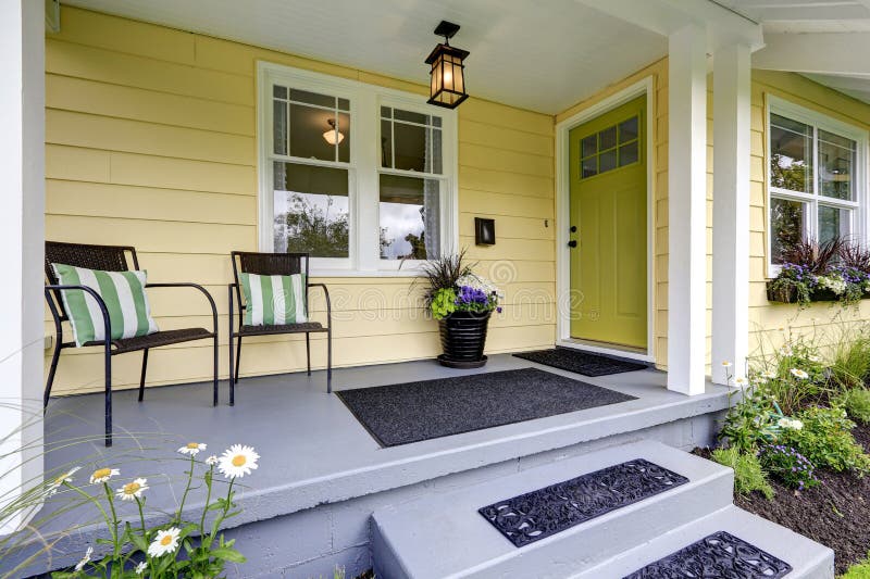 Small American yellow house exterior. Covered porch with stairs. Northwest, USA. Small American yellow house exterior. Covered porch with stairs. Northwest, USA