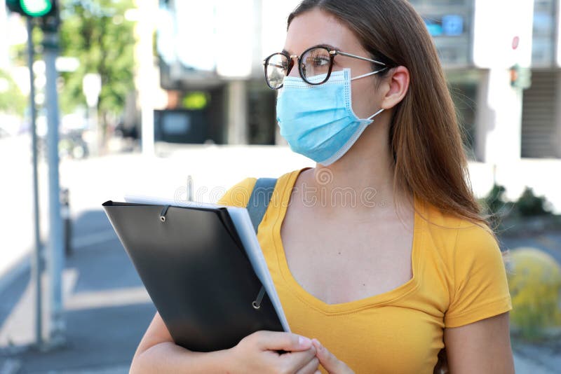 COVID-19 Beautiful University Student Female with Surgical Mask Walking in City Street. College Girl Back to School after Pandemic stock photo COVID-19 Beautiful University Student Female with Surgical Mask Walking in City Street. College Girl Back to School after Pandemic stock photo
