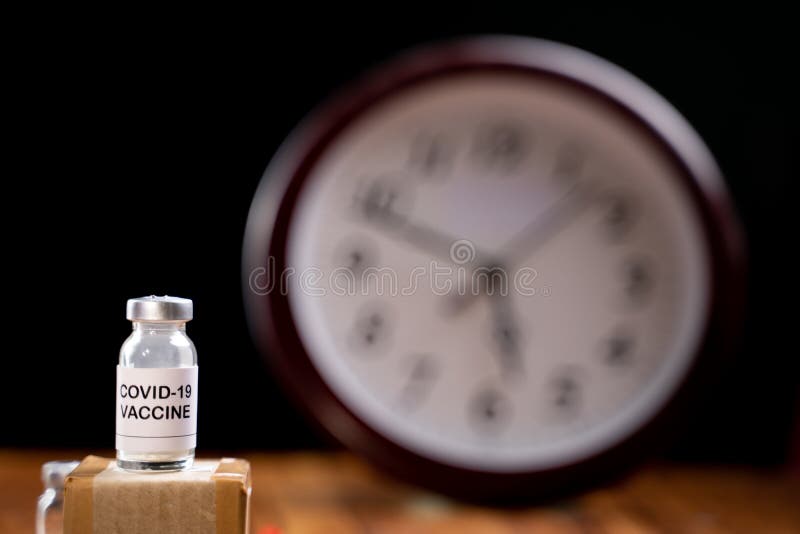 Covid-19 coronavirus vaccination bottle with clock Behind, concept of covid-19 vaccine immunity duration and second dose time