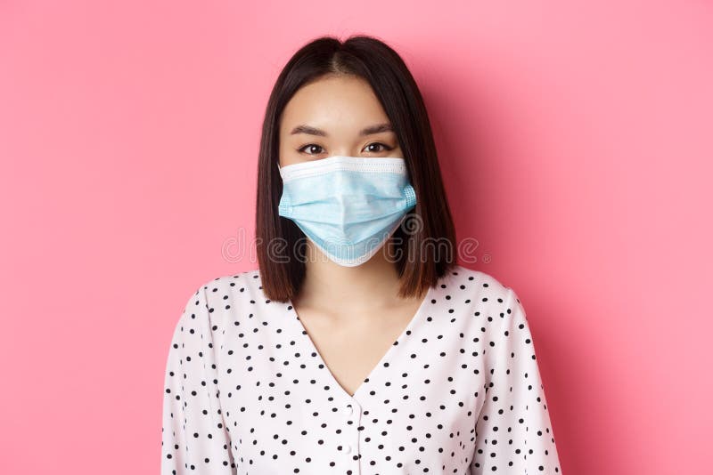 Covid-19, pandemic and lifestyle concept. Close-up of beautiful asian woman in face mask smiling with eyes, wearing