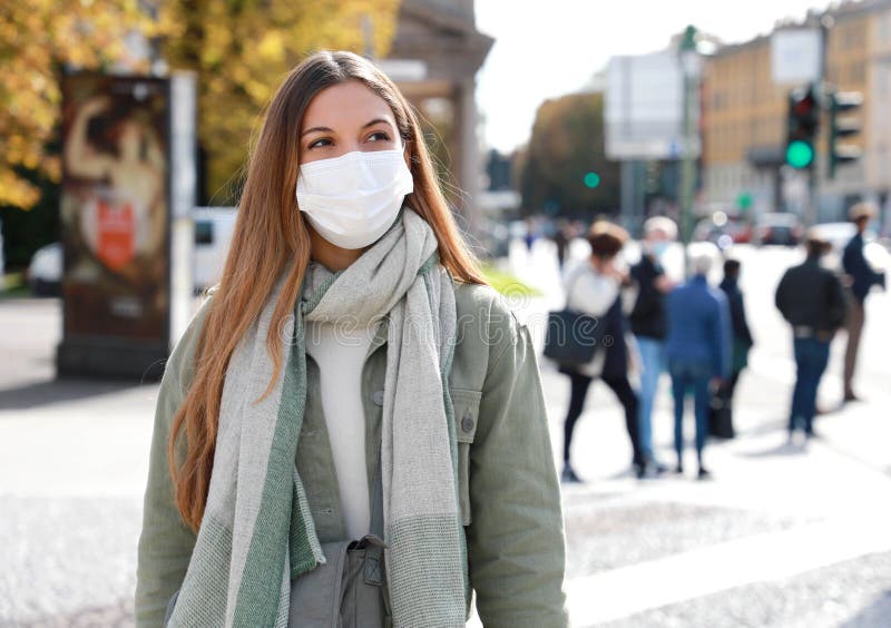 COVID-19 Social Distancing Woman in city street wearing surgical mask against disease virus SARS-CoV-2. Girl with face mask walks