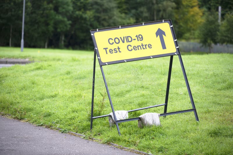 Covid-19 test centre sign at road with traffic cones