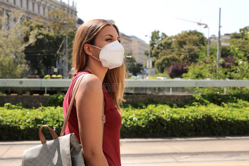 COVID-19 Woman in city street wearing KN95 FFP2 mask protective for spreading of disease virus SARS-CoV-2. Girl with protective