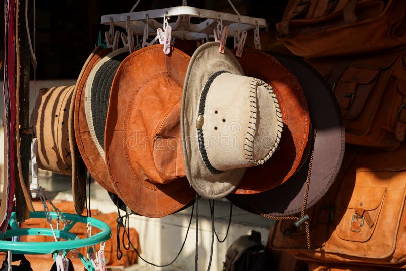 Cowboy Christmas. American West traditional pure leather hats displayed outdoors for sale in sunlight. They are hanging next to