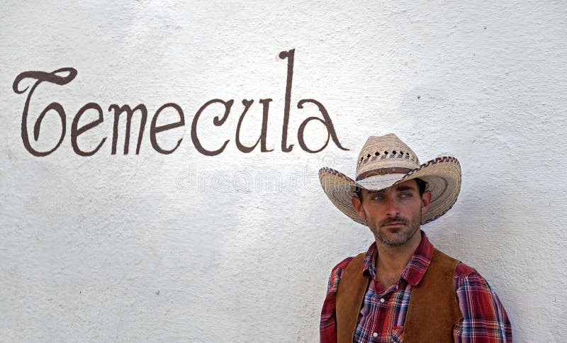 A cowboy leans against a wall.