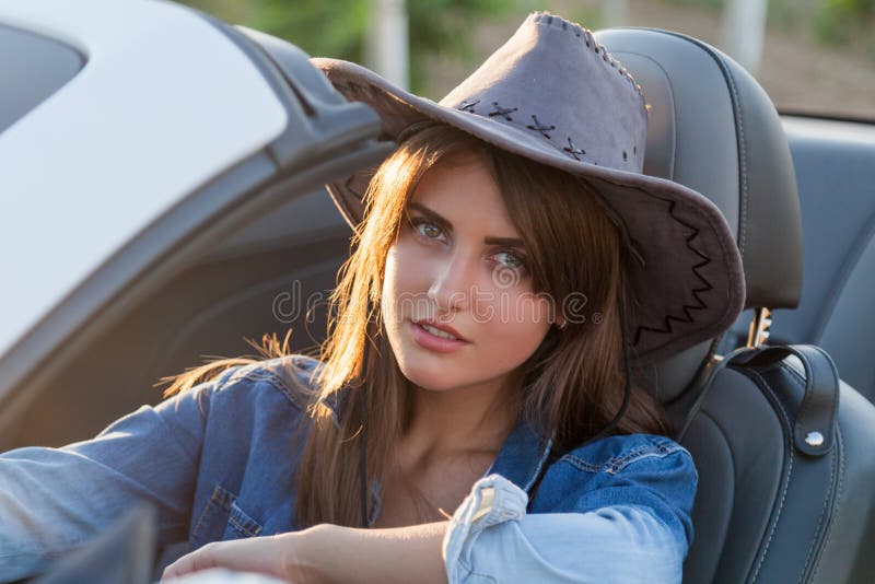 Cowboyflickachaufför i den vita cabrioleten royaltyfri bild Cowboyflickachaufför i den vita cabrioleten royaltyfri bild