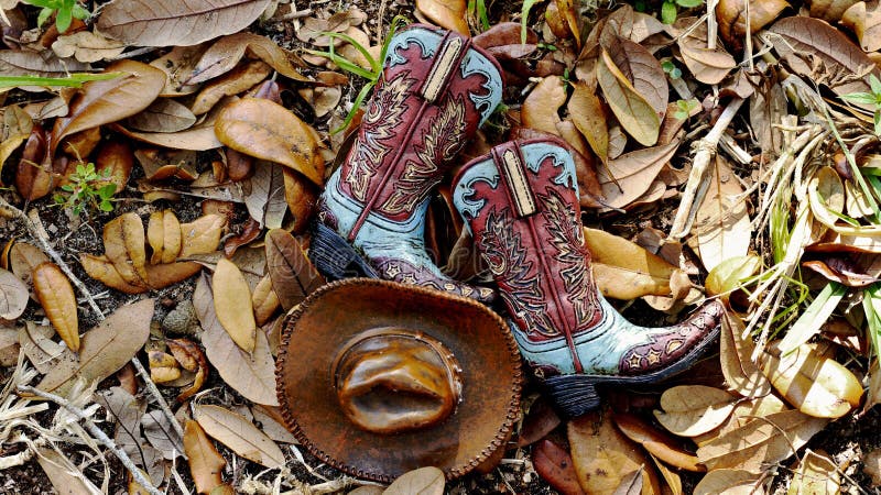 Cowboykängor och hatt som framlänges lägger i en säng av sidor royaltyfria bilder Cowboykängor och hatt som framlänges lägger i en säng av sidor royaltyfria bilder