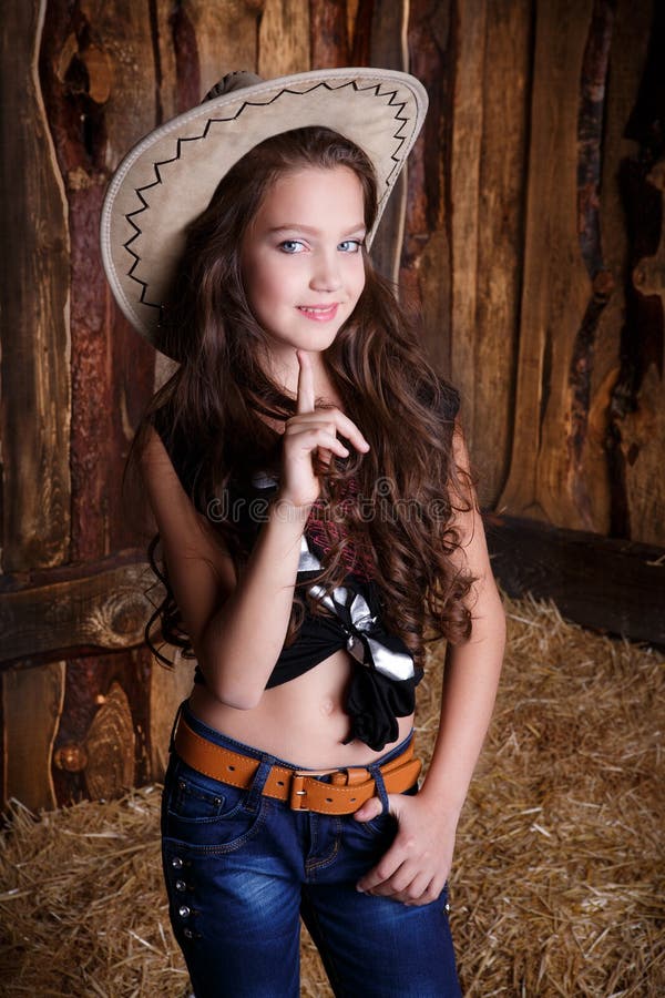 cowgirl style model posing on farmland near hay