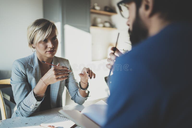 Coworkers som hemma arbetar process Ung blond kvinna som arbetar samman med skäggig kollegaman på den moderna inrikesdepartemente royaltyfri bild Coworkers som hemma arbetar process Ung blond kvinna som arbetar samman med skäggig kollegaman på den moderna inrikesdepartemente royaltyfri bild