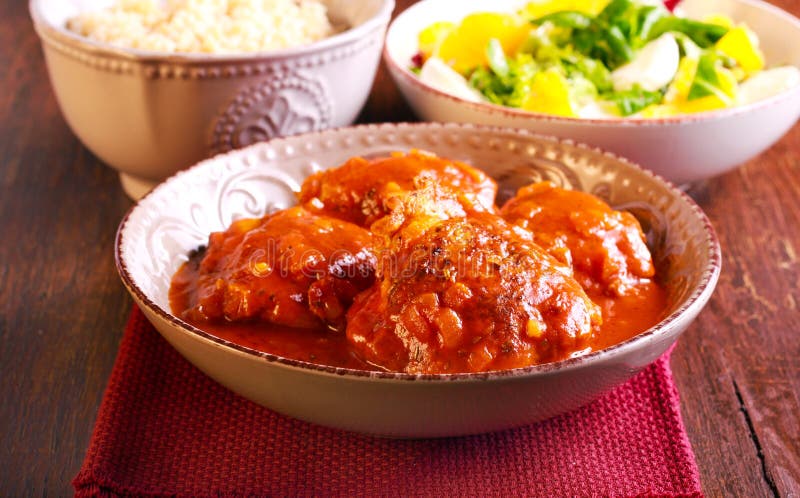 Chicken thighs in spicy tomato sauce in a bowl. Chicken thighs in spicy tomato sauce in a bowl
