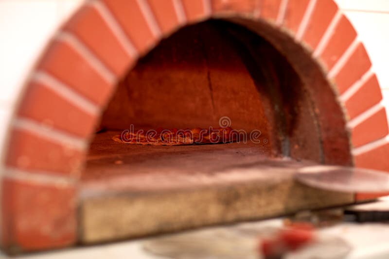 Food, italian kitchen and cooking concept - pizza baking in oven at pizzeria. Food, italian kitchen and cooking concept - pizza baking in oven at pizzeria