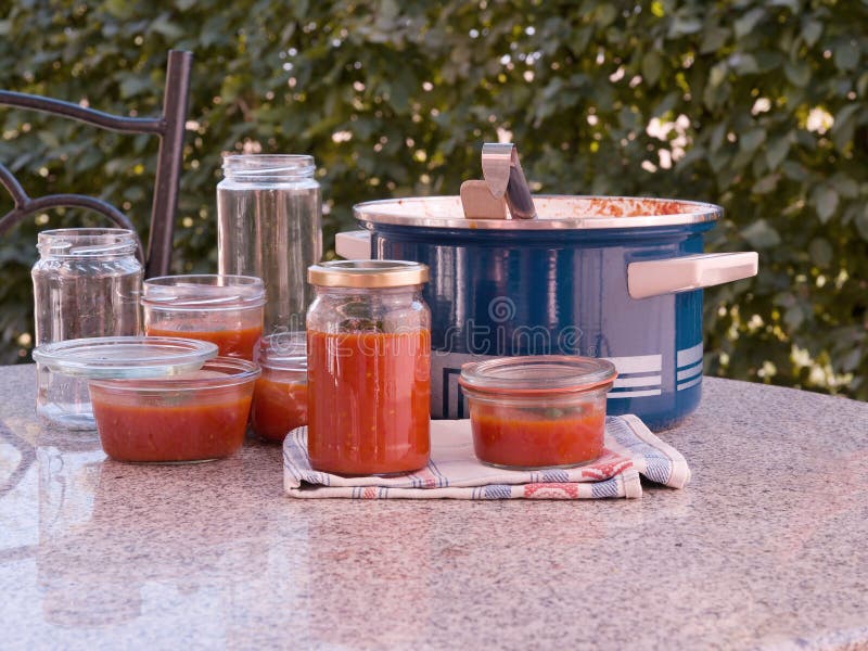 Cozinhando o molho de tomate caseiro do estilo italiano e preservating nos frascos preservating no jardim fotografia de stock royalty free Cozinhando o molho de tomate caseiro do estilo italiano e preservating nos frascos preservating no jardim fotografia de stock royalty free