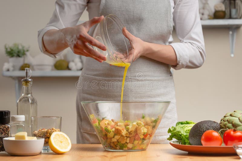 cozinhar O cozinheiro chefe derrama o molho na salada, em processo de uma salada do vegetariano na cozinha da casa Fundo claro imagem de stock royalty free cozinhar O cozinheiro chefe derrama o molho na salada, em processo de uma salada do vegetariano na cozinha da casa Fundo claro imagem de stock royalty free