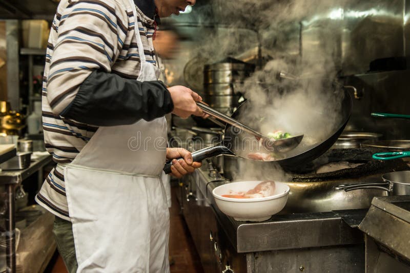 Cozinheiro chefe na cozinha do restaurante no fogão com bandeja fotografia de stock royalty free Cozinheiro chefe na cozinha do restaurante no fogão com bandeja fotografia de stock royalty free