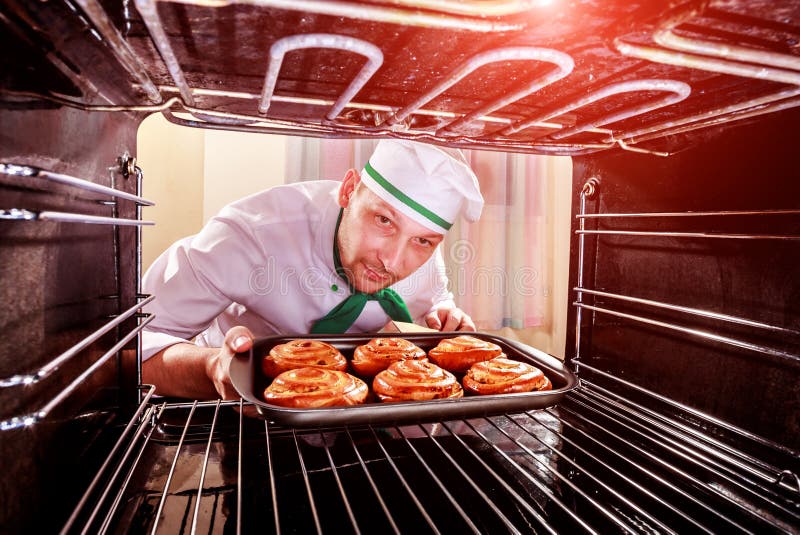 Cozinheiro chefe que cozinha no forno fotografia de stock royalty free Cozinheiro chefe que cozinha no forno fotografia de stock royalty free