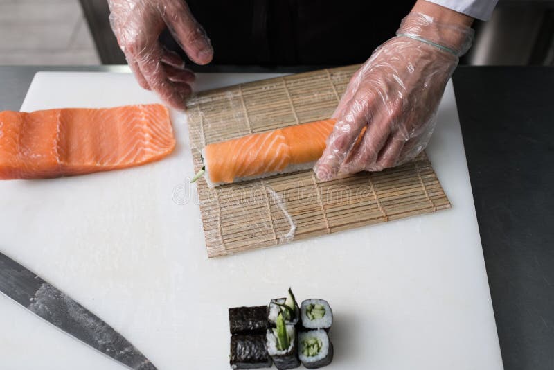Cozinheiro chefe que prepara os rolos de sushi de Philadelphfia salmon foto de stock royalty free Cozinheiro chefe que prepara os rolos de sushi de Philadelphfia salmon foto de stock royalty free