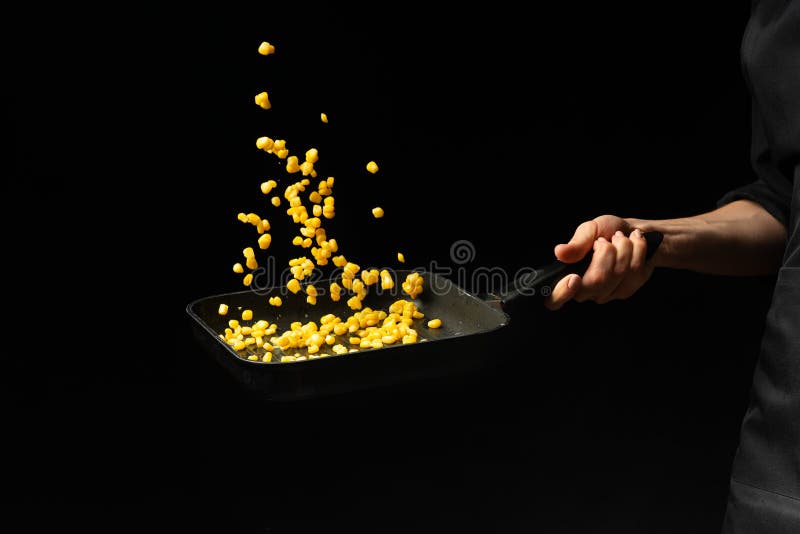 Cozinheiro profissional O cozinheiro chefe está preparando um prato com milho em uma bandeja Em um fundo preto menu, livro da rec fotos de stock Cozinheiro profissional O cozinheiro chefe está preparando um prato com milho em uma bandeja Em um fundo preto menu, livro da rec fotos de stock