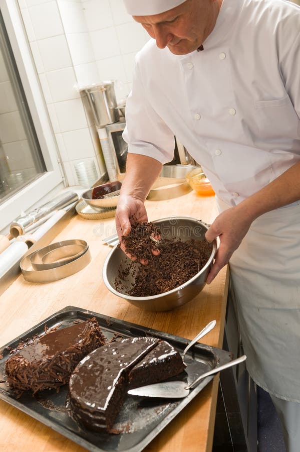 Cozinheiro que adiciona o bolo do molho de chocolate na cozinha