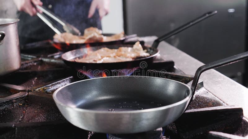 Cozinheiros cozinhando fatias de carne em panelas na cozinha de restaurantes fechar