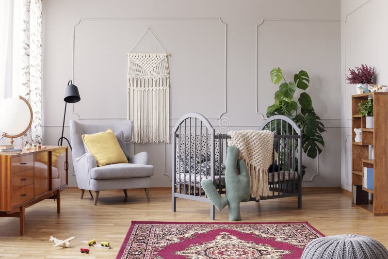Comfortable armchair and grey wooden crib, real photo