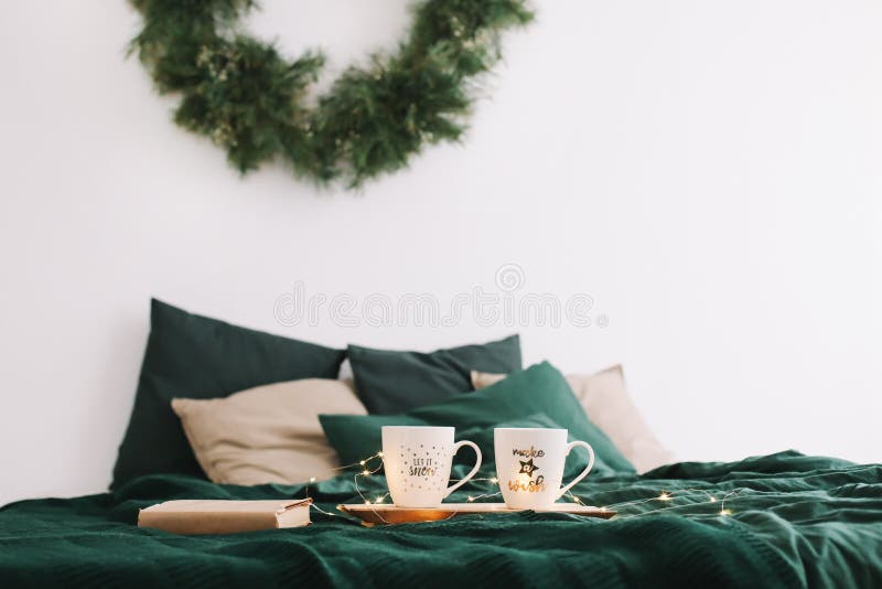 Cozy bedroom with coffee mugs and book in bed. Christmas still life. Holidays, Christmas and New Year concept