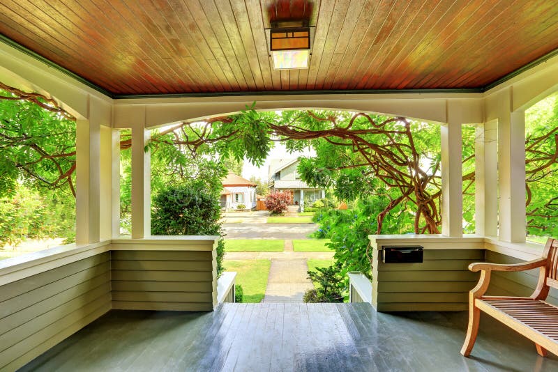 Cozy covered porch interior with wooden bench.