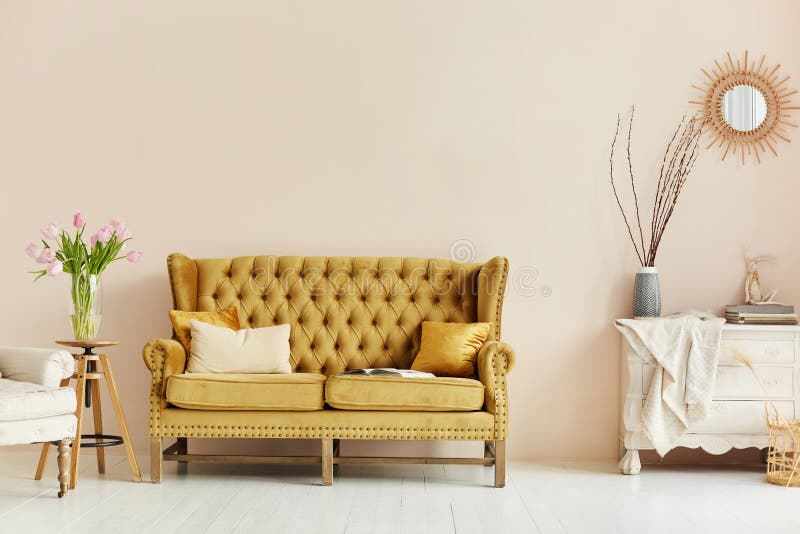 Cozy living room interior of retro armchair, vintage wooden chest dwarf and vintage couch on the background of the beige wall and painted wooden floor.