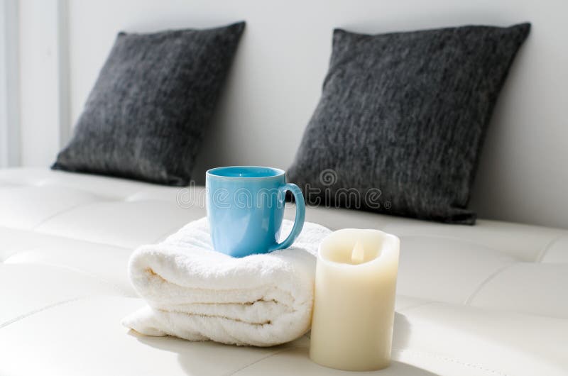 Cozy look, candle and coffee mug on white towel