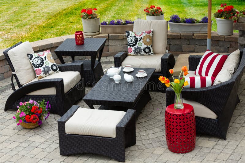 Cozy Patio Furniture on Luxury Outdoor Patio. Overview of Upscale Patio Set, Dark Wicker Luxury Furniture with Comfortable Cushions on Outdoor Stone Patio of royalty free stock photography