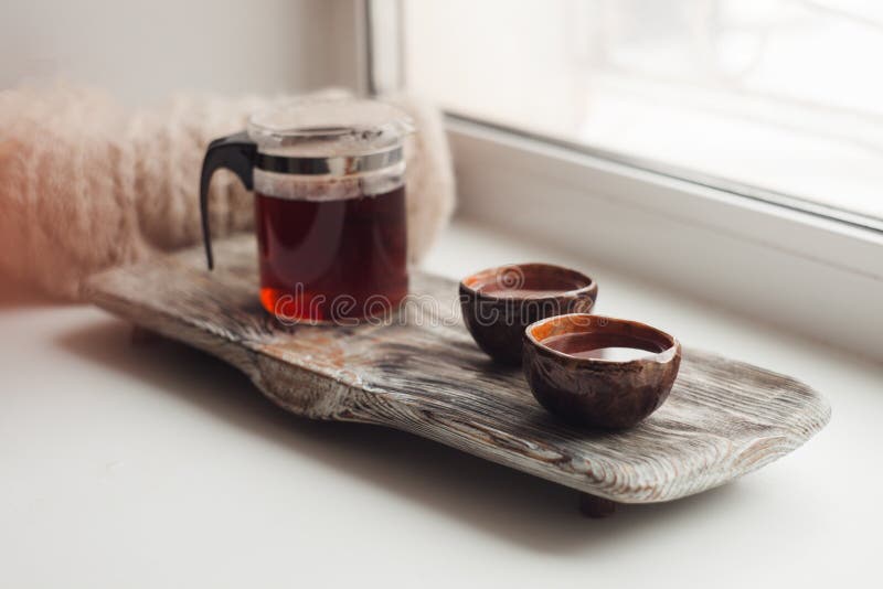 A cozy place to read on the windowsill - Asian tea, a warm scarf, a book, an atmosphere of coziness, inspiration, relaxation stock image A cozy place to read on the windowsill - Asian tea, a warm scarf, a book, an atmosphere of coziness, inspiration, relaxation stock image
