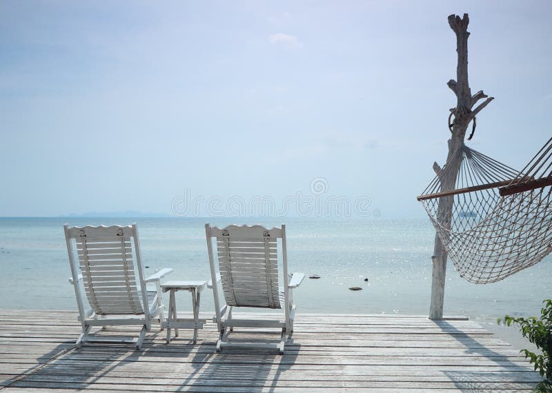 white beach chair and hammock facing seascape