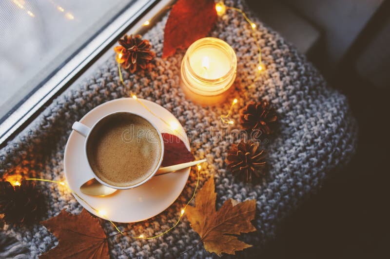 Cozy winter or autumn morning at home. Hot coffee with gold metallic spoon, warm blanket, garland and candle lights