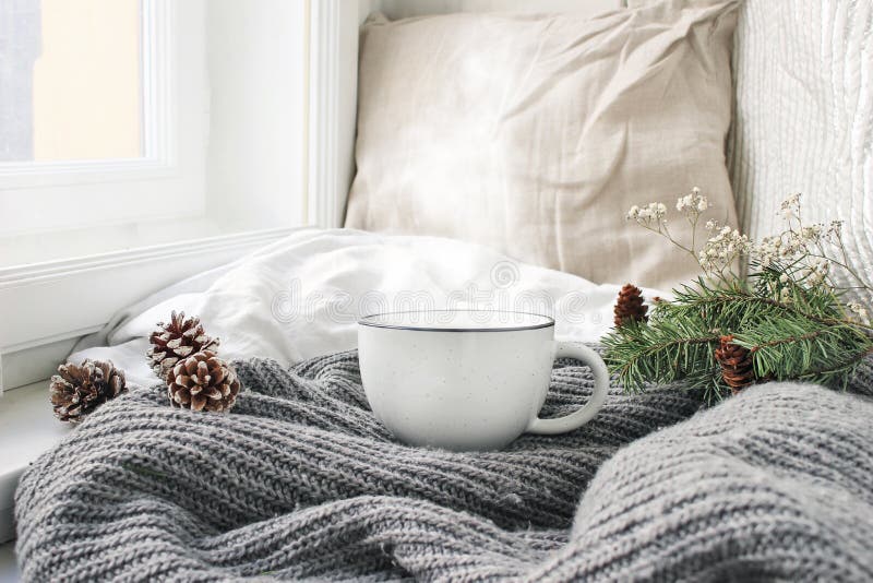 Cozy winter morning breakfast in bed still life scene. Steaming cup of hot coffee, tea standing near window. Christmas