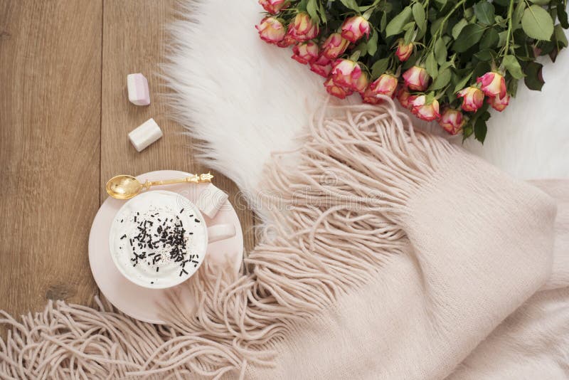 Cozy Winter Mornings. Cappuccino, bouquet of roses and a warm scarf on a white fur carpet on the floor stock photography Cozy Winter Mornings. Cappuccino, bouquet of roses and a warm scarf on a white fur carpet on the floor stock photography