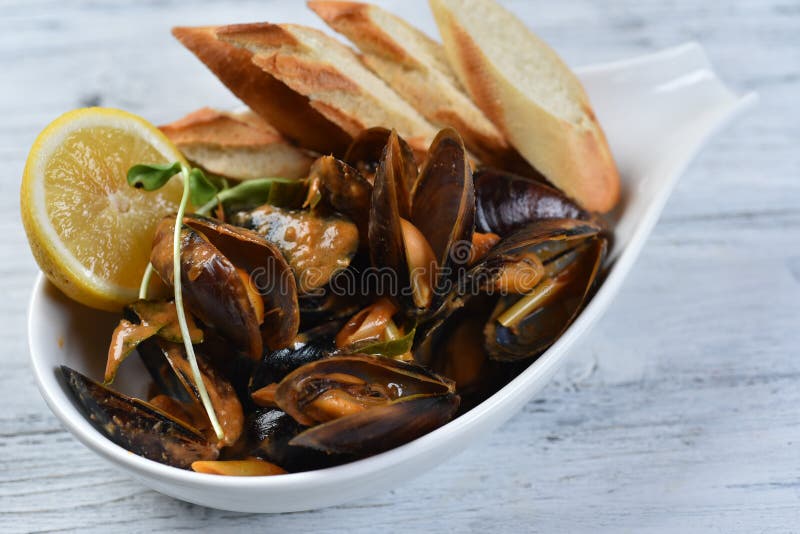 Cozze in conchiglia con salsa crotolone limone e germogli in una piastra bianca immagini stock
