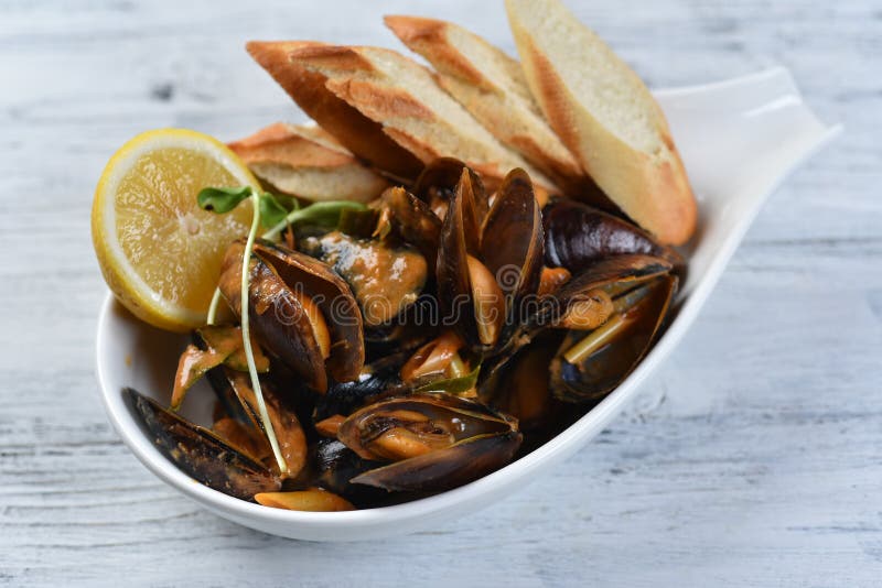 Cozze in conchiglia con salsa crotolone limone e germogli in una piastra bianca fotografia stock libera da diritti