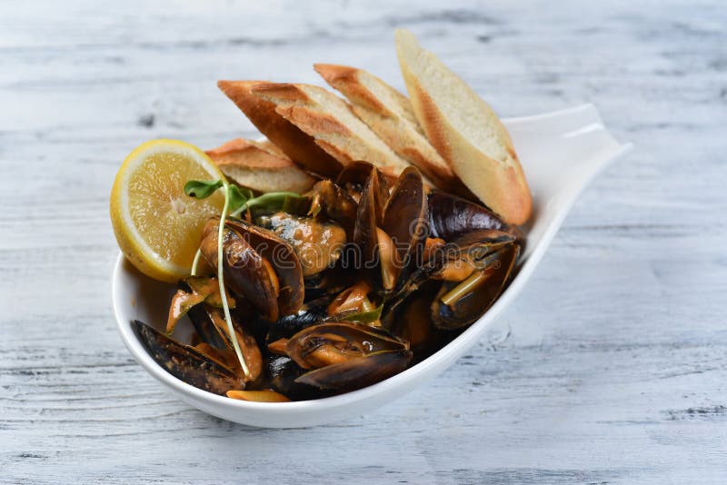 Cozze in conchiglia con salsa crotolone limone e germogli in una piastra bianca immagini stock libere da diritti
