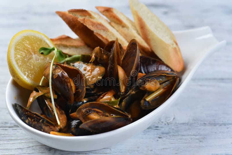 Cozze in conchiglia con salsa crotolone limone e germogli in una piastra bianca. Cozze in conchiglia con salsa crostini limone e germogli