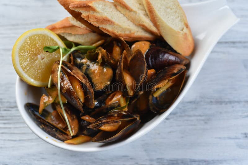 Cozze in conchiglia con salsa crotolone limone e germogli in una piastra bianca fotografie stock