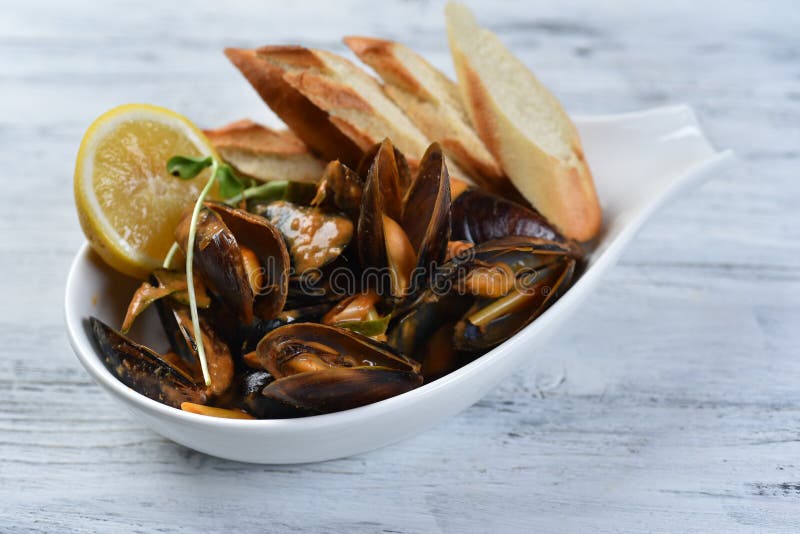 Cozze in conchiglia con salsa crotolone limone e germogli in una piastra bianca immagine stock libera da diritti