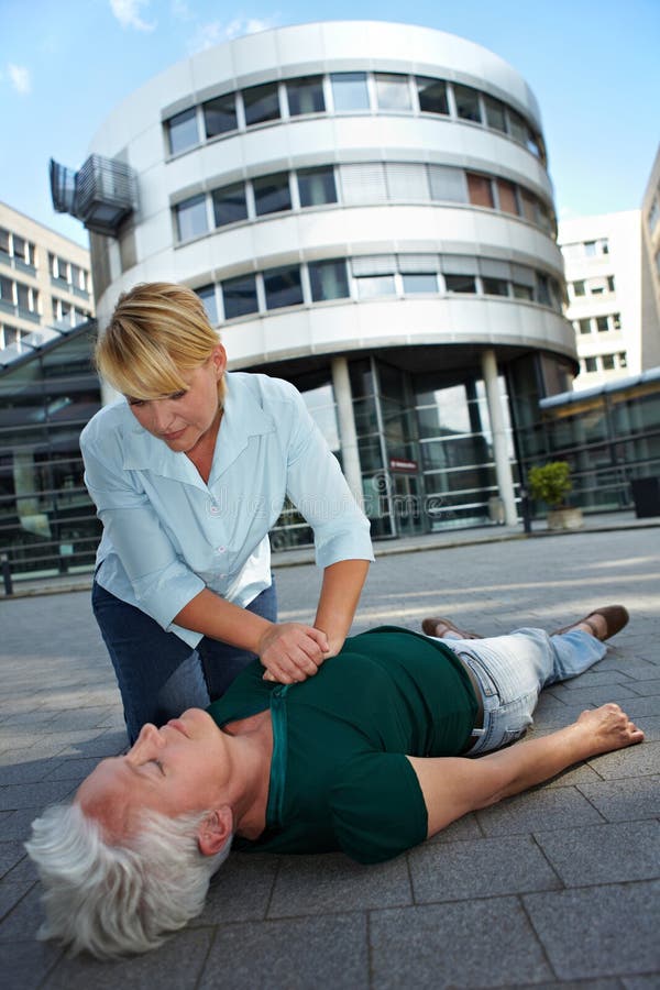 Passerby giving CPR to senior women as First Aid. Passerby giving CPR to senior women as First Aid