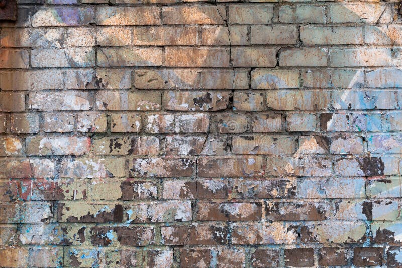 Cracked brick wall background with multiple layers of paint stock photo